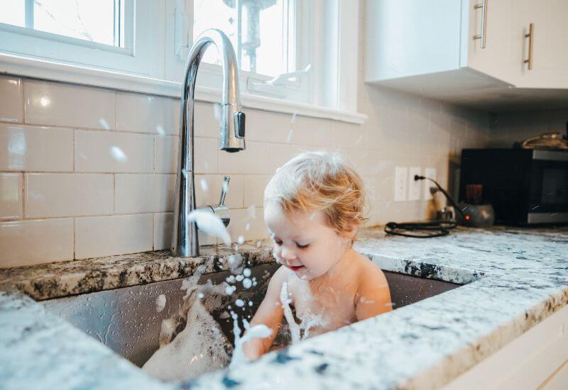 Baby splashing water in kitchen sink