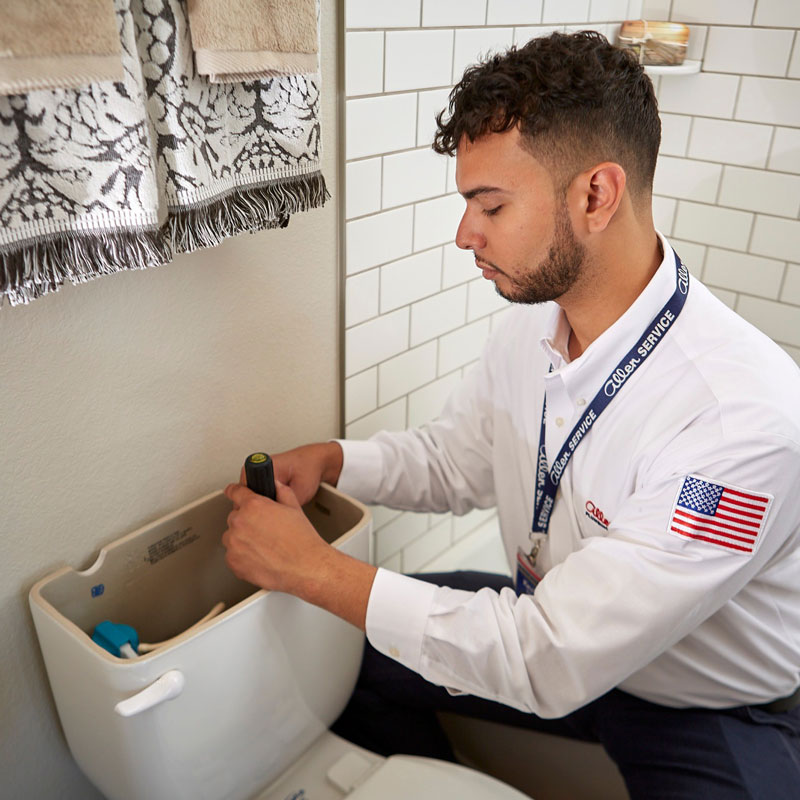 An Allen Service technician repairing the back of a toilet in the Fort Collins, Colorado, area